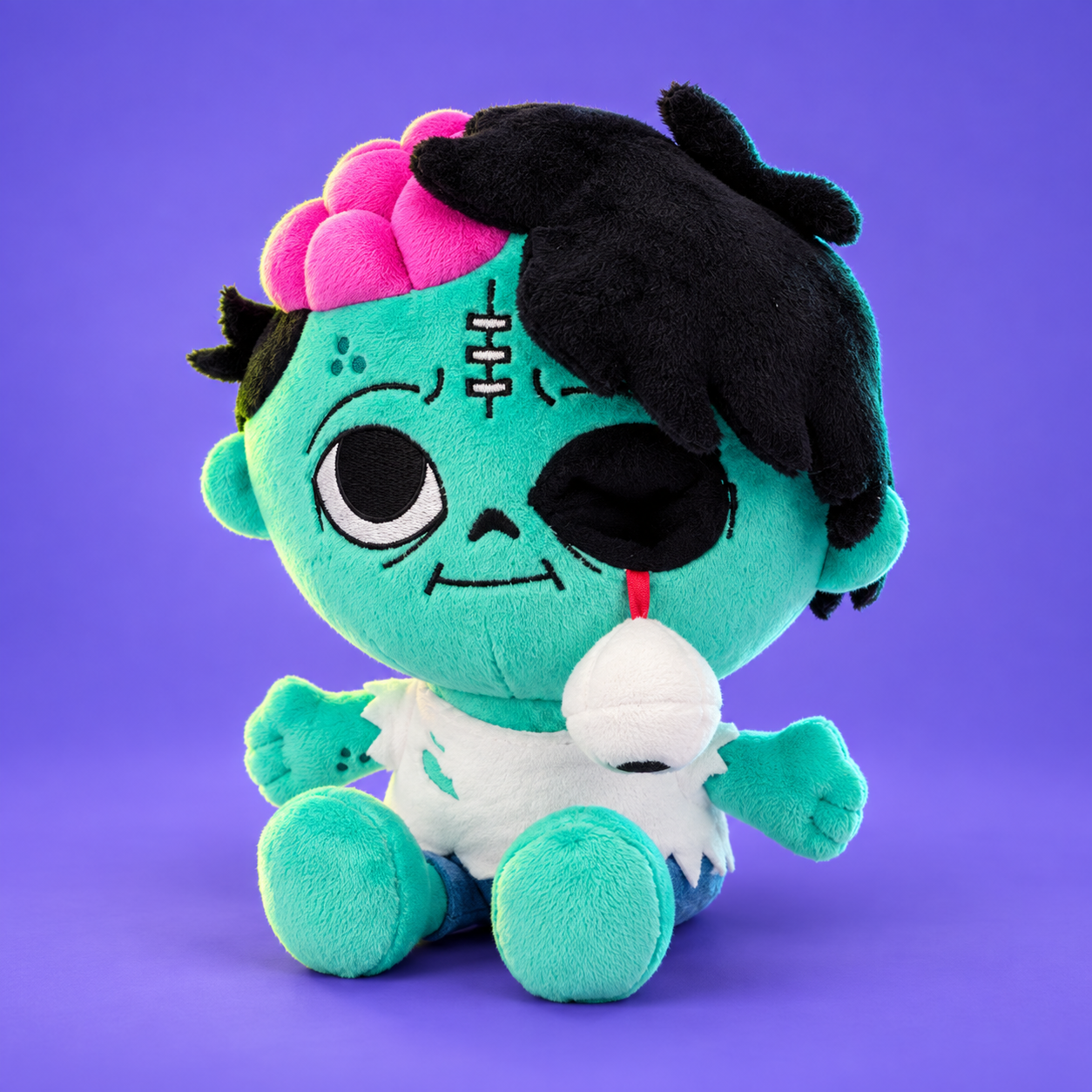 Our turquoise zombie plushie, with a pink plush brain, black hair and a dangling eyeball